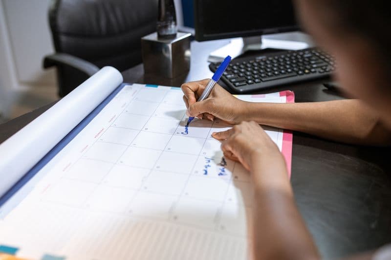 Hand marking a date on a desk calendar